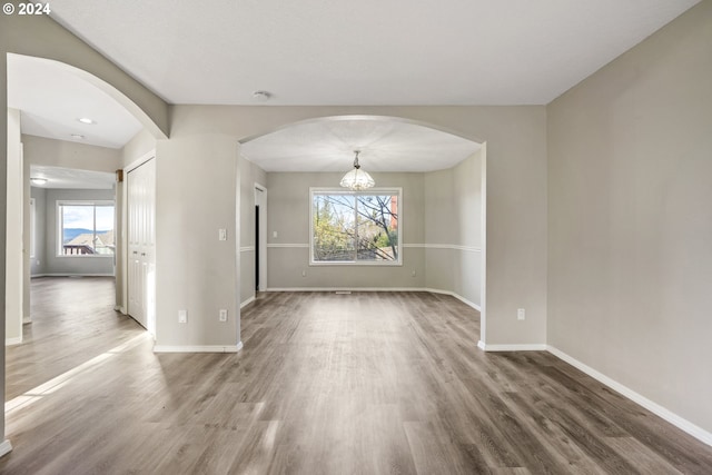 unfurnished dining area with hardwood / wood-style floors and a notable chandelier