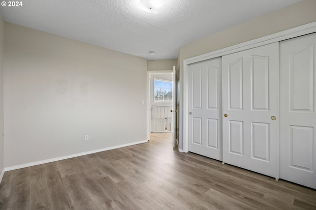 unfurnished bedroom with a closet, a textured ceiling, and light hardwood / wood-style flooring