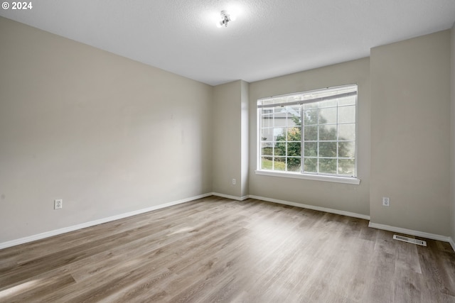 unfurnished room with light hardwood / wood-style floors and a textured ceiling