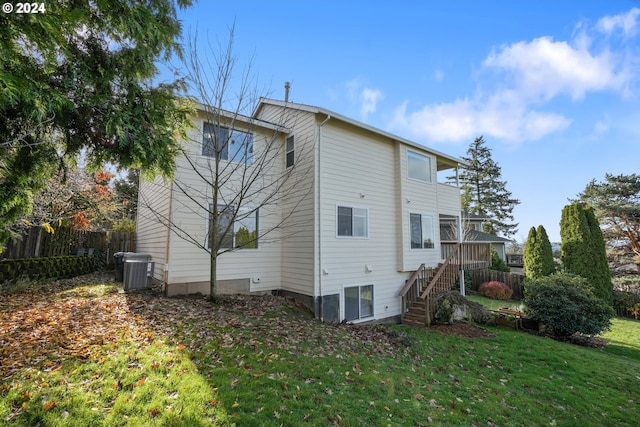 back of house featuring a yard, central air condition unit, a deck, and a sunroom