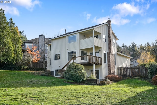 rear view of house featuring a balcony, a yard, and a wooden deck