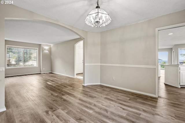 unfurnished room featuring hardwood / wood-style flooring, a notable chandelier, and a textured ceiling