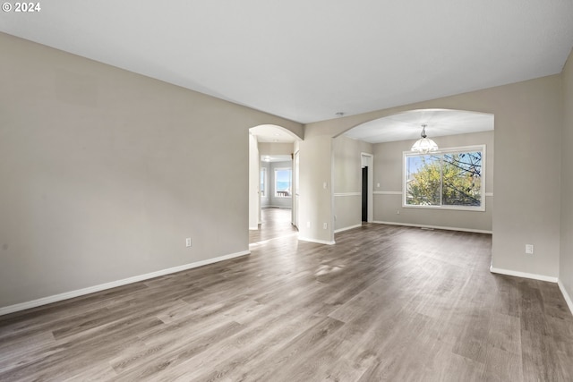 unfurnished living room featuring a chandelier and wood-type flooring