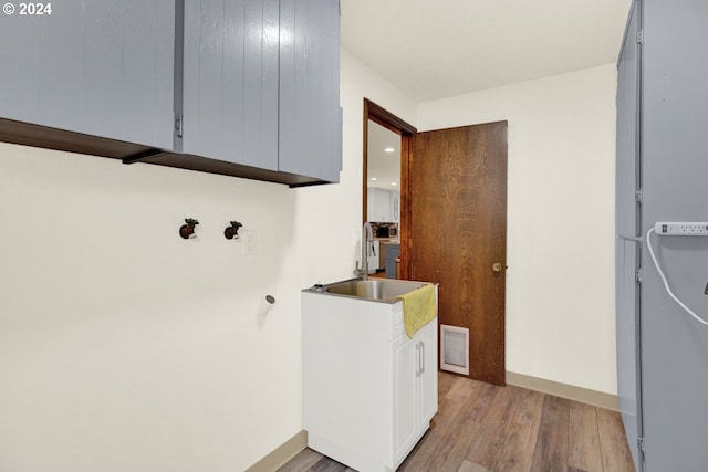 washroom with cabinets, sink, and light hardwood / wood-style floors