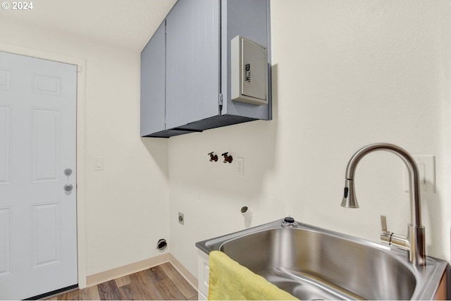 clothes washing area featuring electric dryer hookup, cabinets, sink, and hardwood / wood-style flooring