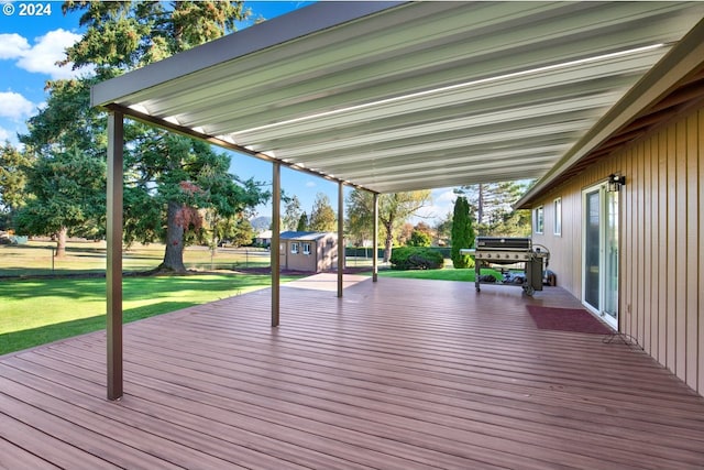 wooden terrace with area for grilling, a lawn, and a storage unit