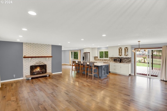 kitchen with light wood-type flooring, appliances with stainless steel finishes, hanging light fixtures, and a healthy amount of sunlight