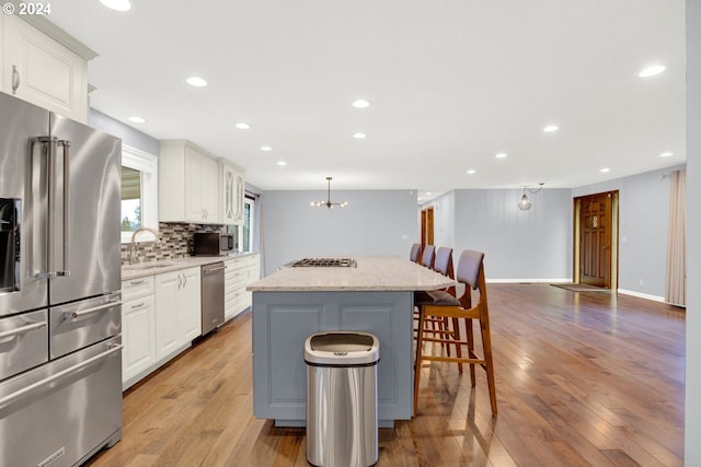 kitchen featuring light wood-type flooring, white cabinetry, a kitchen island, and appliances with stainless steel finishes