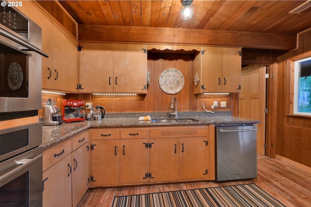 kitchen with sink, stainless steel appliances, light hardwood / wood-style flooring, wooden walls, and wood ceiling