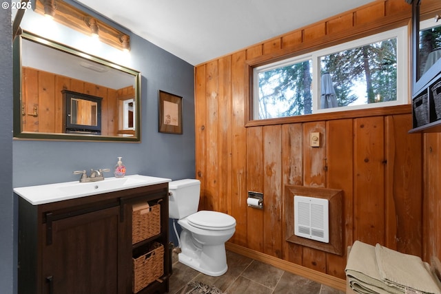 bathroom featuring vanity, toilet, and wooden walls