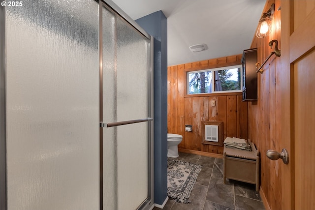 bathroom with wood walls, toilet, and a shower with shower door