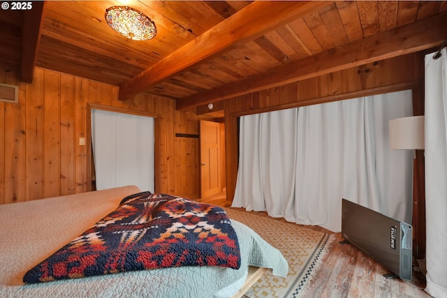 bedroom with wooden walls, beamed ceiling, and light wood-type flooring