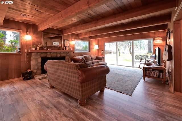 living room with a fireplace, beamed ceiling, hardwood / wood-style flooring, and wooden walls