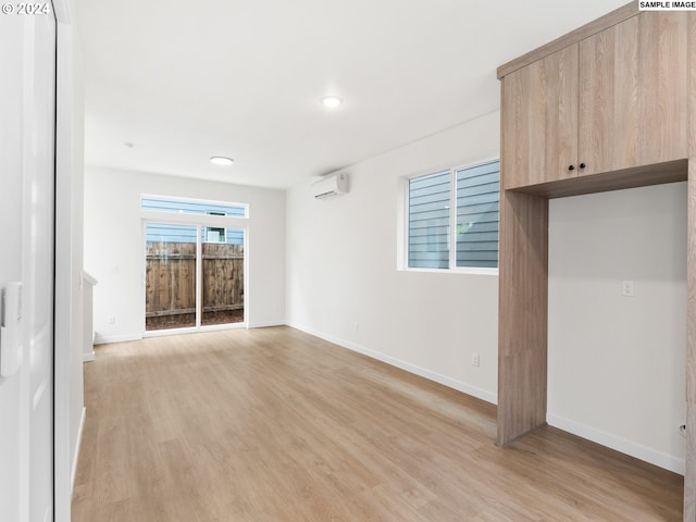 unfurnished living room with light wood-type flooring and a wall unit AC