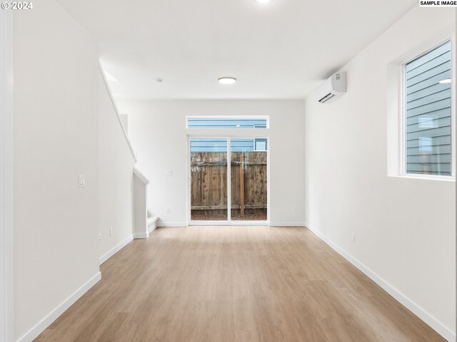 unfurnished living room with light wood-type flooring and a wall unit AC