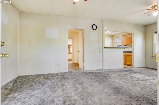 unfurnished living room featuring light carpet and ceiling fan