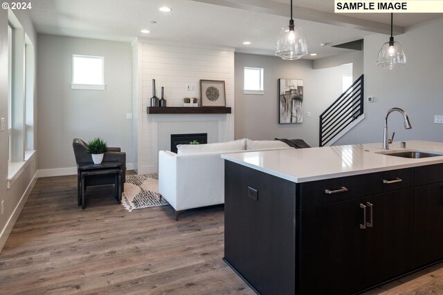 kitchen with a large fireplace, a wealth of natural light, a kitchen island with sink, and sink