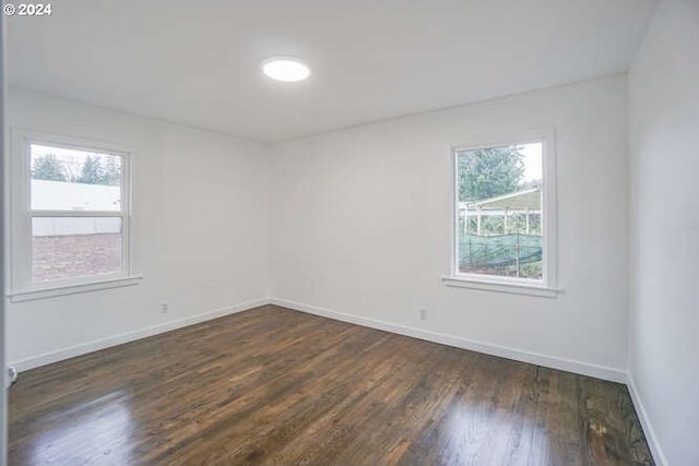 unfurnished room featuring a healthy amount of sunlight and dark hardwood / wood-style floors