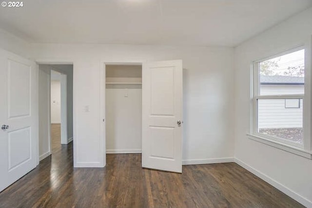 unfurnished bedroom with a closet and dark wood-type flooring