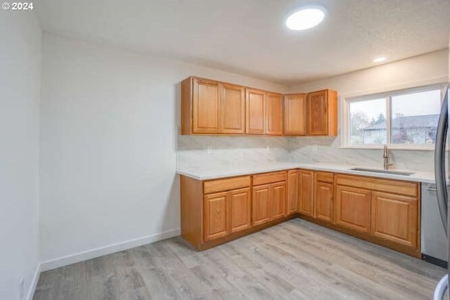 kitchen featuring tasteful backsplash, sink, and light hardwood / wood-style flooring