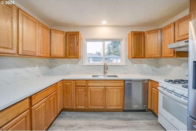 kitchen with sink, white gas range oven, stainless steel dishwasher, decorative backsplash, and light wood-type flooring