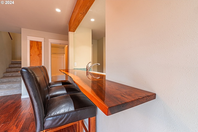 bar featuring dark hardwood / wood-style floors and beam ceiling