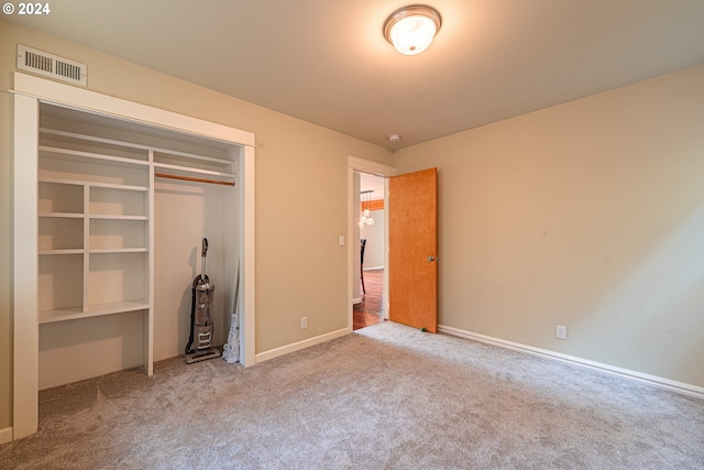 unfurnished bedroom featuring light colored carpet and a closet