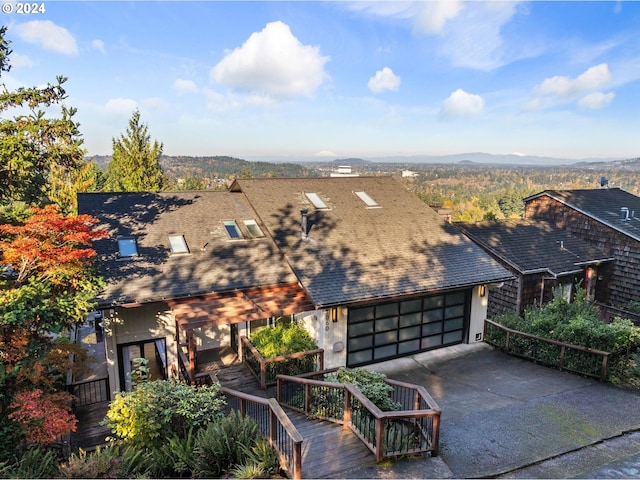 view of front of home featuring an attached garage, driveway, a mountain view, and roof with shingles