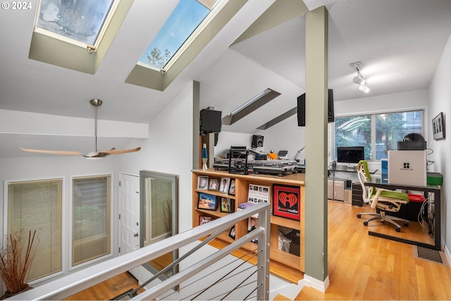 corridor with lofted ceiling with skylight and wood finished floors