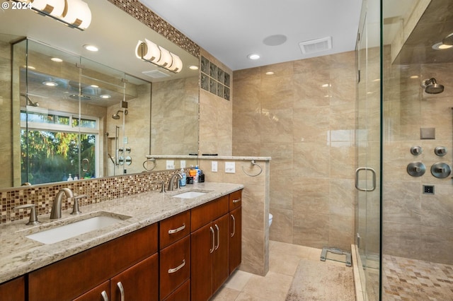 bathroom with visible vents, a sink, tile walls, and a shower stall