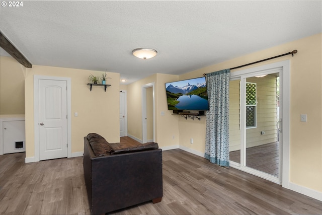 living area featuring baseboards, a textured ceiling, and wood finished floors