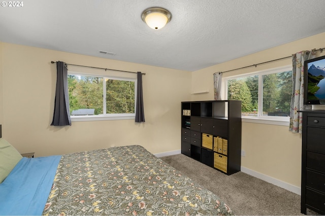 carpeted bedroom featuring baseboards, visible vents, and a textured ceiling