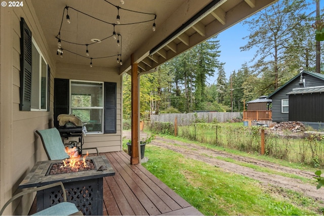 wooden terrace featuring a fire pit, fence, and grilling area