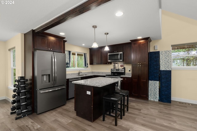 kitchen featuring a sink, stainless steel appliances, dark brown cabinets, light wood-style floors, and a center island