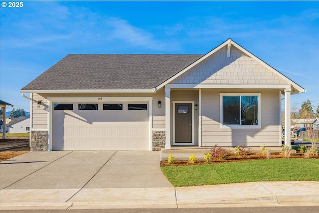 view of front of home featuring driveway, stone siding, roof with shingles, and an attached garage