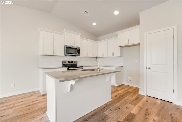 kitchen with a kitchen island with sink, sink, stainless steel appliances, and white cabinets