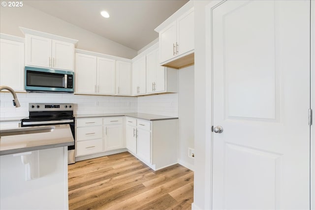 kitchen with white cabinetry, tasteful backsplash, stainless steel appliances, and light hardwood / wood-style flooring