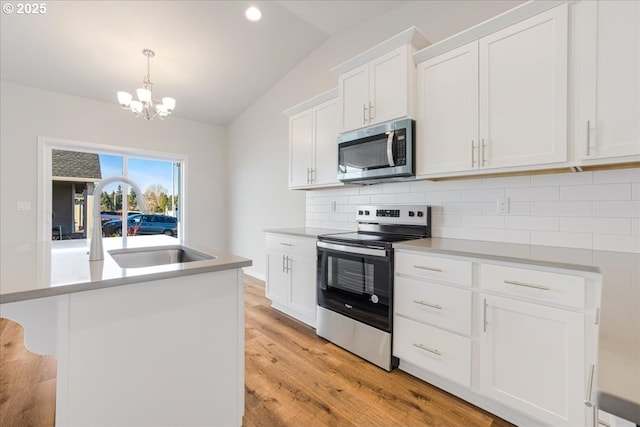 kitchen with lofted ceiling, tasteful backsplash, a center island, stainless steel appliances, and white cabinets