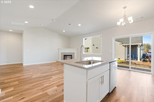 kitchen with white cabinetry, dishwasher, sink, a premium fireplace, and a center island with sink