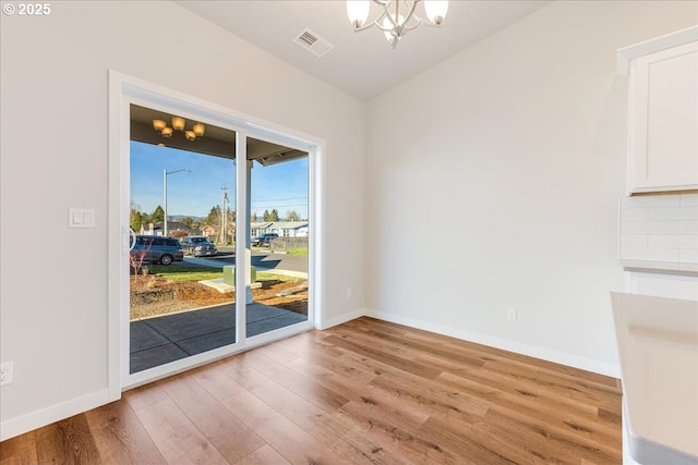 unfurnished dining area featuring a chandelier and light hardwood / wood-style floors