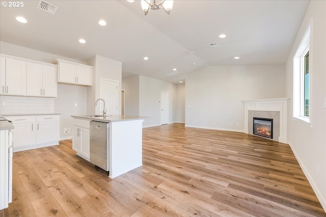 kitchen with sink, a kitchen island with sink, white cabinetry, light hardwood / wood-style floors, and stainless steel dishwasher