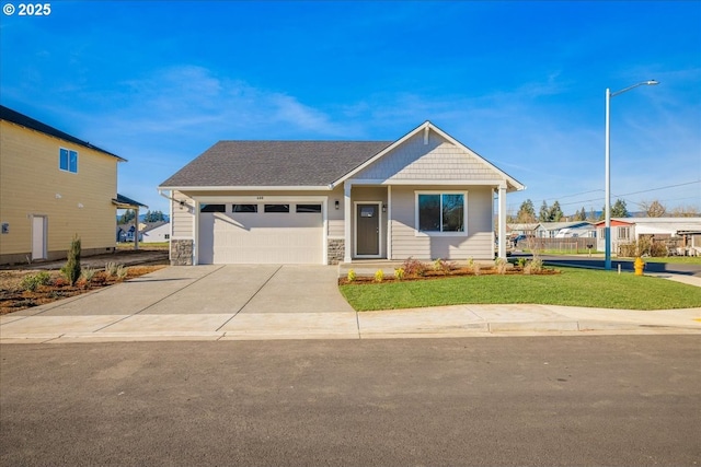 view of front facade with a shingled roof, an attached garage, stone siding, driveway, and a front lawn