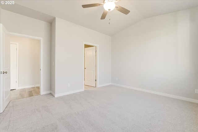 carpeted spare room featuring vaulted ceiling and ceiling fan