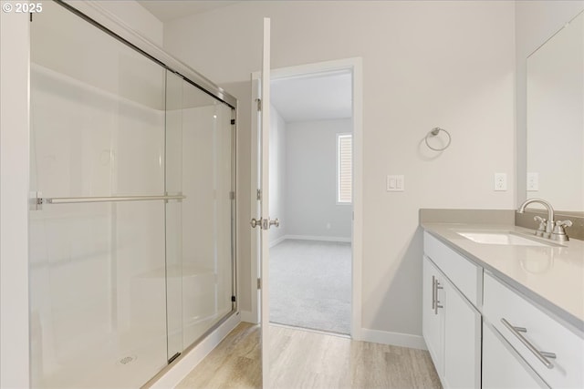 bathroom featuring vanity, a shower with shower door, and wood-type flooring