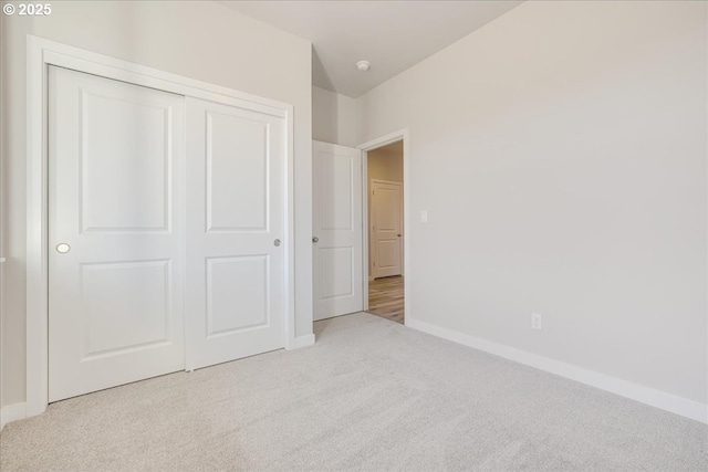 unfurnished bedroom featuring light colored carpet and a closet