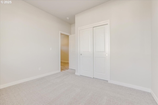 unfurnished bedroom with light carpet and a closet