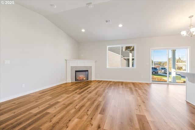 unfurnished living room with an inviting chandelier, lofted ceiling, and light wood-type flooring