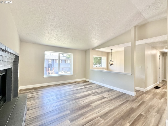 unfurnished living room with a textured ceiling, wood-type flooring, a fireplace, and lofted ceiling