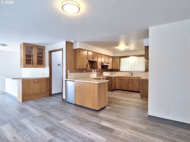 kitchen with a textured ceiling, kitchen peninsula, sink, and light hardwood / wood-style flooring