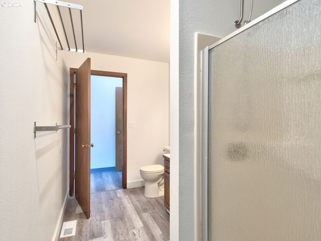 bathroom with vanity, hardwood / wood-style flooring, toilet, and a shower with door